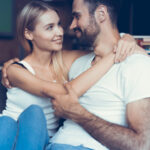 пара сидит в обнимку на диване и смотрит друг другу в глаза