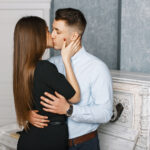 пара стоит в обнимку и целуется возле пианино